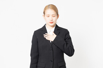 胸に手を当てるジャケットを着た若い女性