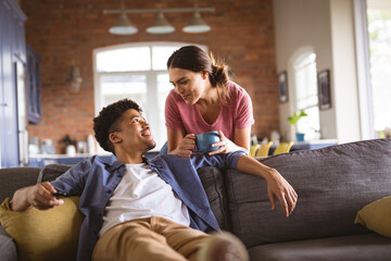 Happy young loving biracial couple looking at each other in living room