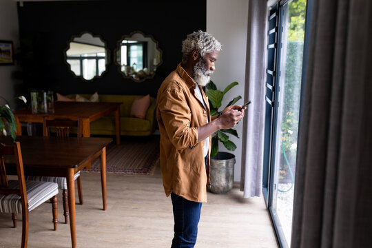 Side view of bearded senior african american man text messaging on smartphone at home