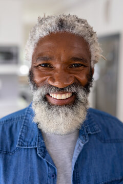 Close-up portrait of smiling african american senior man with white hair and beard at home