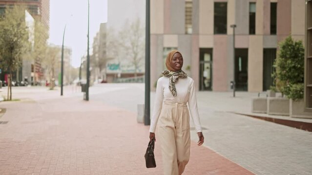 Stylish Muslim female walking on pavement
