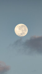 Obraz na płótnie Canvas Luna llena en un amanecer con nubes