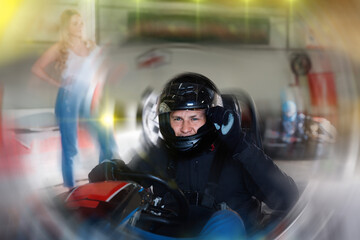 Diligent efficient positive man in helmet driving car for karting in sport club, friendly smiling...