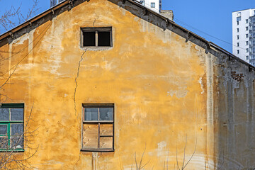 The facade of an old abandoned house against the backdrop of an urban landscape