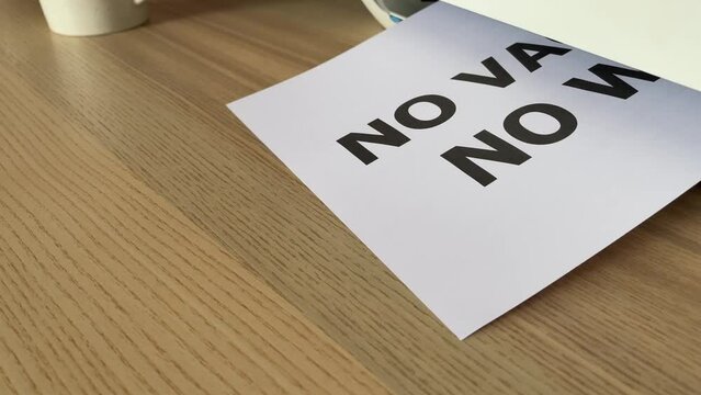 Printing of &ldquo;NO VACCINE NO WORK&rdquo; text written on paper sheet document. Close up footage A4 page being printed. Office worker male hand take paper from multifunction printer scanner on desk in office