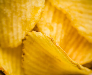Salty grooved chips in ceramic bowl on the rustic background. Selective focus. Shallow depth of field.