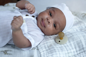Cute 2 months old Muslim baby boy wearing white hat and Muslim Men's robe costume lying on bed
