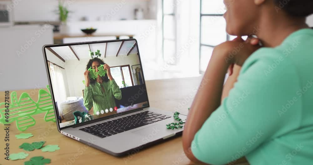 Poster Smiling african american woman wearing clover shape items on video call on laptop