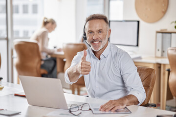 Another day, another happy client. Shot of a mature man using a headset and showing thumbs up in a modern office.