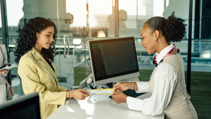 Young business woman at check-in counter with airlines staff. Airline transportation and tourism...