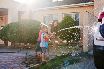 This car is going to be squeaky clean. Shot of a family washing their car in the driveway.