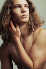 Gazing into the distance. A handsome young shirtless man with long blonde hair.