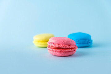 Colorful french macarons cookies (macaroons) on blue background. Dessert, vegetarian sweets close up
