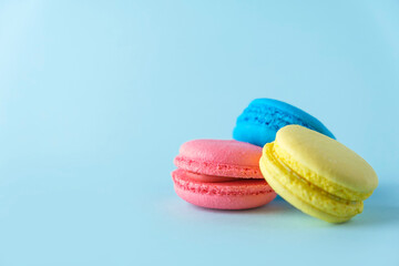 Fototapeta na wymiar Colorful french macarons cookies (macaroons) on blue background. Dessert, vegetarian sweets close up