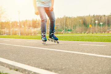 The boy is rollerblading in motion in a sports park. Legs close up