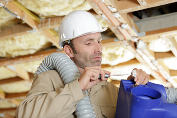 man installing ventilation system in property under renovation