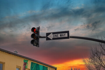 a traffic signal with a red light and a black and white one way sign with blue sky and majestic red...