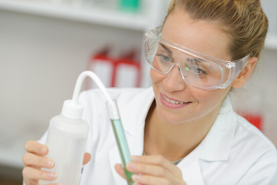 positive minded woman smiling while looking at a test tube
