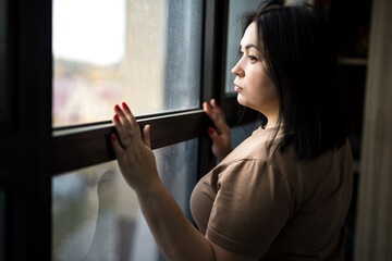 A young woman stands near the observation windows and looks at the city.