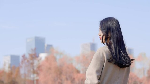 young beautiful woman standing in city park

