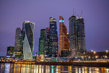 Fototapeta premium Moscow City International Business Centre skyscraper buildings with panoramic windows night view. Moscow City at night. Lights are reflected in the river.