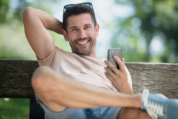 happy handsome man sitting on the bench outdoors