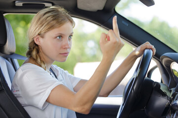 young woman shows middle finger while driving