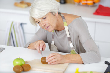 Obraz na płótnie Canvas a senior woman cutting tomatos
