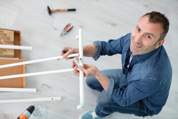 man is assembling furniture at home