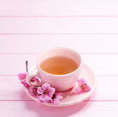 Cup of tea and spring  flowers  (Peach blossom) on light pink wooden table. Selective focus.