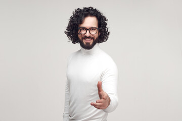 Smiling man reaching hand for handshake in studio