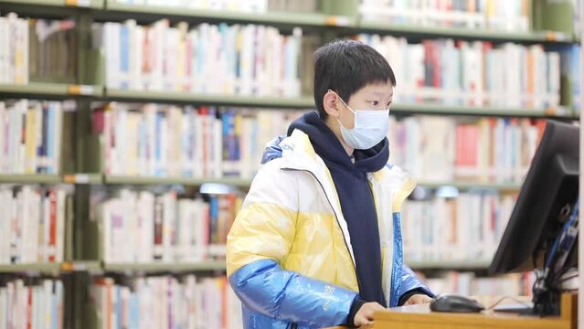 chinese teenager searching book on computer in library
