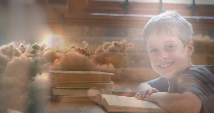 Animation of clauds over caucasian boy reading book