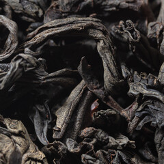 Dried black tea leaves as background.