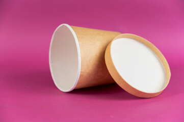 Empty cylindrical paper container with lid opposite-colored background. Brown food container for soup, ice cream, noodles, or other food.