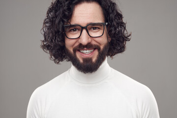 Happy curly haired bearded man in eyeglasses in studio