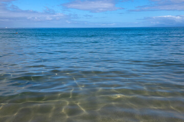 Summer sea background. Texture of water surface. Shining blue water ripple pattern.