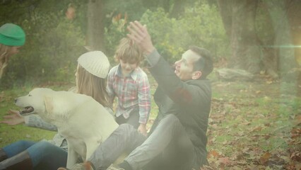 Spot of light against caucasian family playing with their dog in the garden