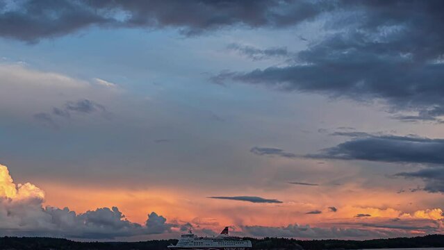 Static view of huge white cruise ship passing by in evening timelapse with dark clouds visible in the sky.