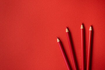 Rote Buntstifte auf rotem Hintergrund. Freiraum für Text
