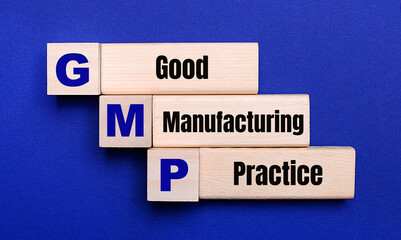 On a bright blue background, light wooden blocks and cubes with the text GMP Good Manufacturing Practice