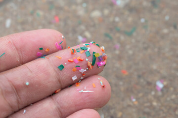 Close-up side shot of hands showing microplastics on the beach. Microplastics are contaminated in...