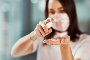 Hand sanitiser kills many harmful germs that could infect your colleagues. Closeup shot of a businesswoman using hand sanitiser in an office.