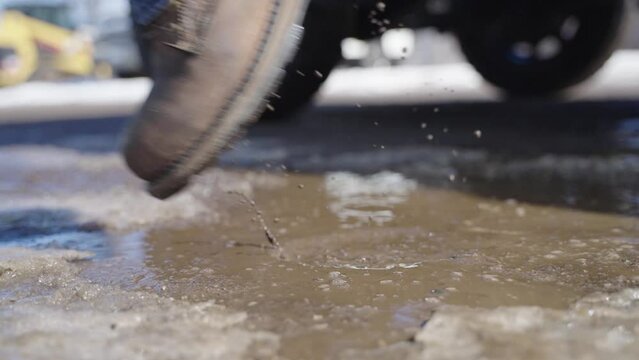 Close up, man's rugged work boots splashing puddle while getting truck. Man wearing jeans. Slow motion. Laborer, men at work, construction manual labor concept
