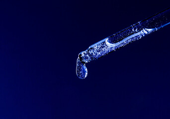 serum pipette with a falling drop on a dark background	
