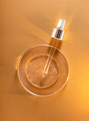 round transparent drop of clear gel serum in petri dish	on gold background	
