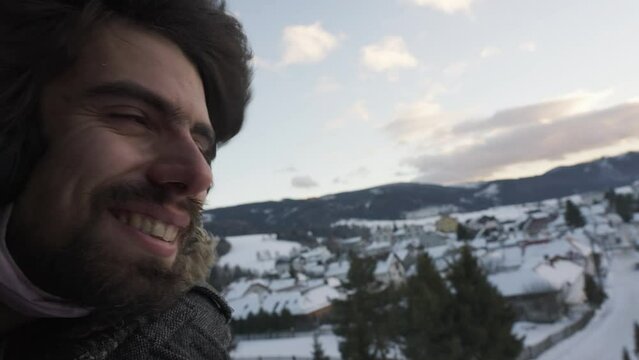 Bearded Male Wearing headphones Smiling With Head Out Of Open Window On Train in snowy winter landscape, Slovakia. traveling adventurer enjoying his journey.