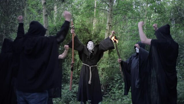 A circle of evil hooded druids in a cult performing a sorcery ritual
