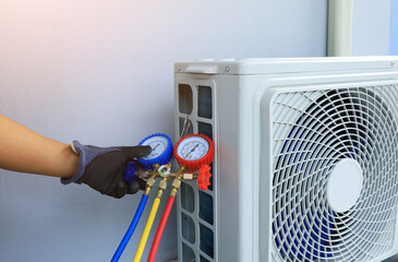 An air conditioner technician's serviceman hand holding a manifold gauge to check the pressure...