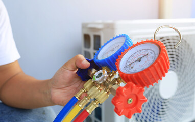 An air conditioner technician's serviceman hand holding a manifold gauge to check the pressure...